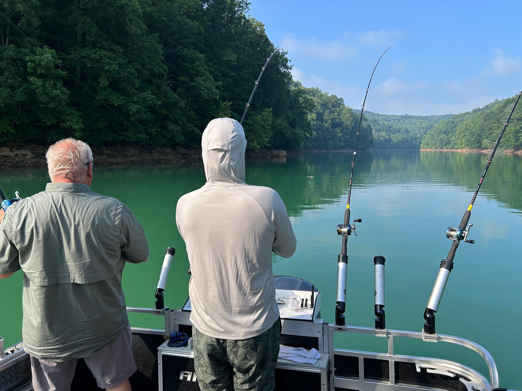 Two anglers fishing off the back of a boat in a quiet cove near Sunset Pointe
